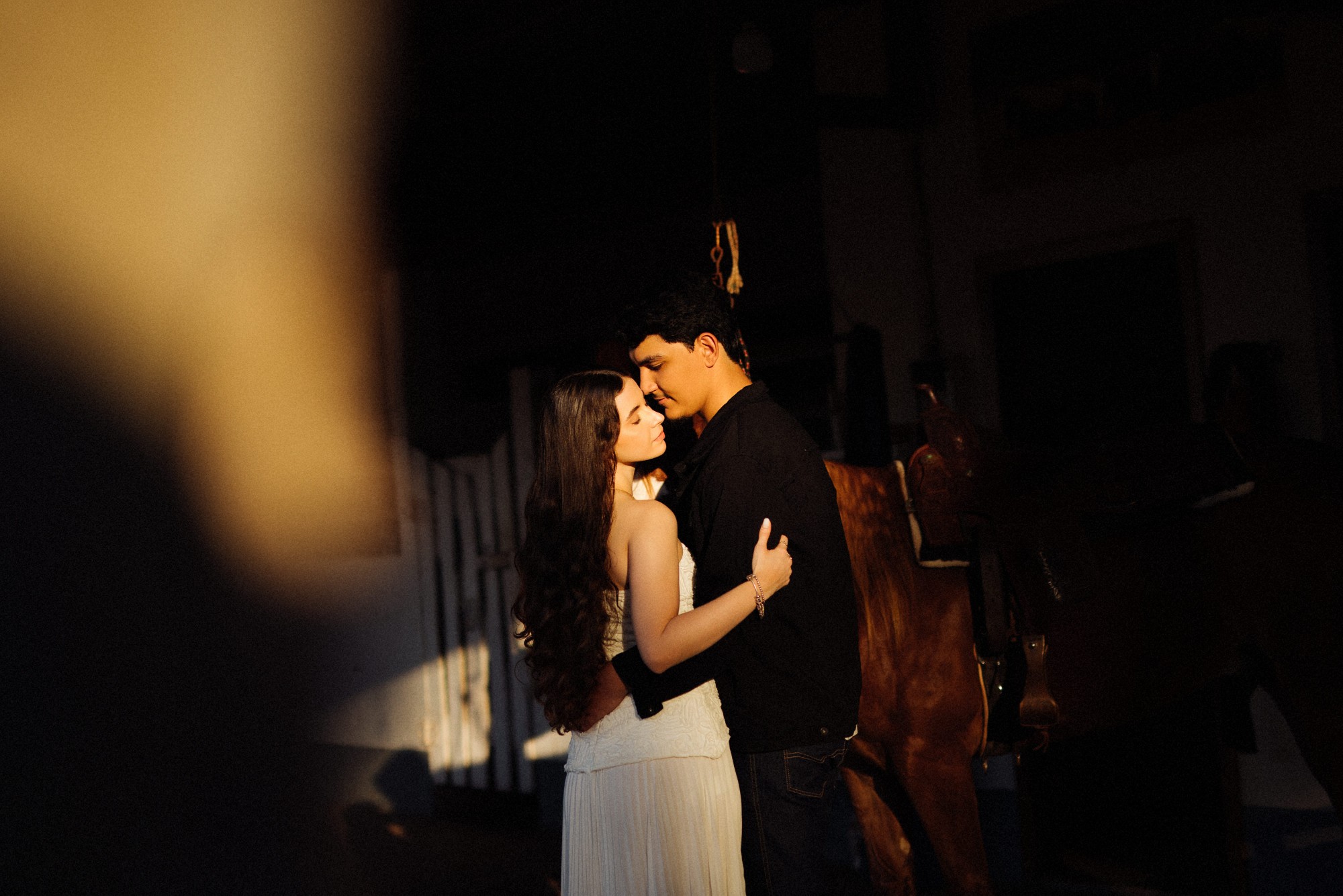 Casal abraçado no celeiro, iluminado pelo sol