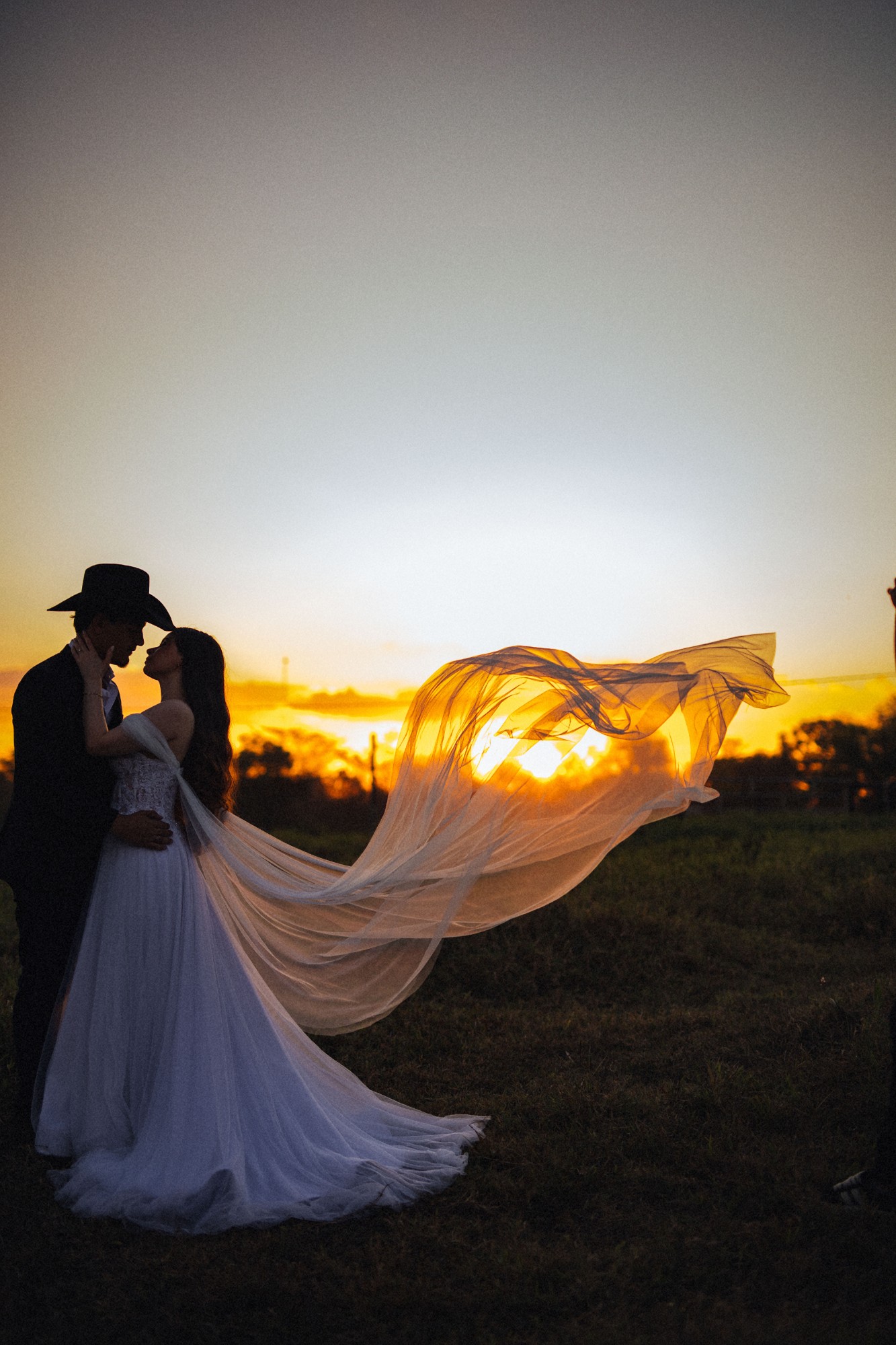 Casal ao pôr do sol, com o véu ao vento